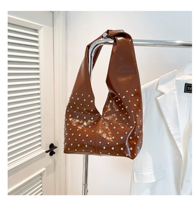 Détail du sac hobo marron brillant avec rivets argentés et large bandoulière intégrée