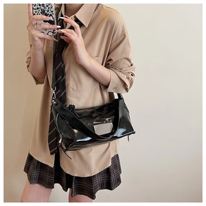 Detail of glossy black patent leather crescent bag with silver zipper and wide strap