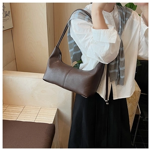 Model wearing a dark brown leather hobo bag in a warm interior setting with a shoulder strap