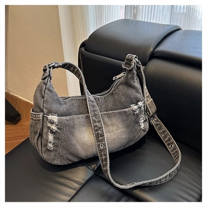 Detail of distressed grey denim hobo bag featuring vintage frayed edges and metal buckle