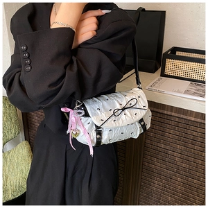 Detail of white pleated shoulder bag featuring black bows and a heart charm