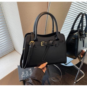 Detail of elegant black matte leather handbag with gold hardware and top handle design