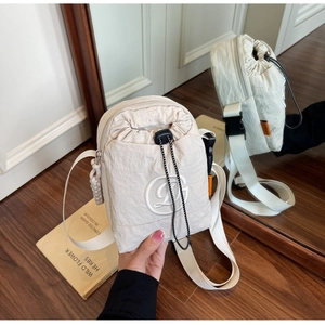 Detail of off-white nylon crossbody bag showing drawstring closure and embroidered logo
