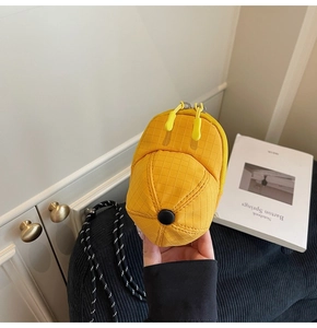 Detailed close-up of a mini yellow baseball cap shaped pouch with textured grid fabric
