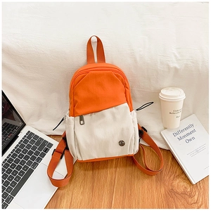 Detailed close-up of orange and beige canvas backpack with adjustable straps and metal logo