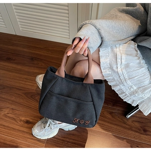 Detail of black canvas bucket bag with vintage letter embroidery and rope handle