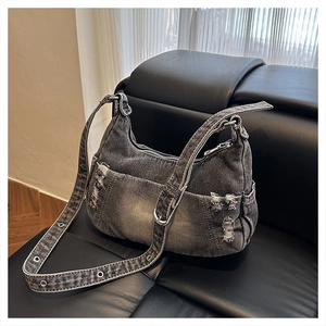 Detail of distressed dark grey denim hobo bag featuring frayed edges and metal eyelets