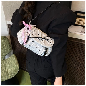 Detail of white pleated crossbody bag with black bow print and pearl ribbon charm