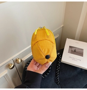 Detailed view of yellow cap-shaped mini coin purse with checkered texture and dual zippers
