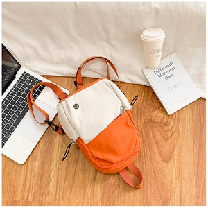 Détail du petit sac à dos en toile crème et orange avec des bretelles réglables