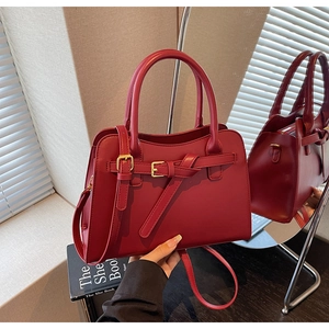 Detail of red leather wedding handbag with gold metal buckle and elegant round handle