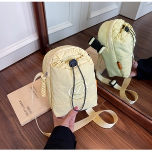 Detail of light yellow nylon drawstring crossbody bag with embroidered D logo