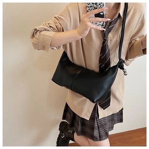 Minimalist black half-moon underarm bag with unique knotted strap and metal ball charm