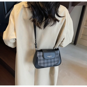 Vue détaillée du sac à bandoulière en cuir à carreaux gris porté par un mannequin