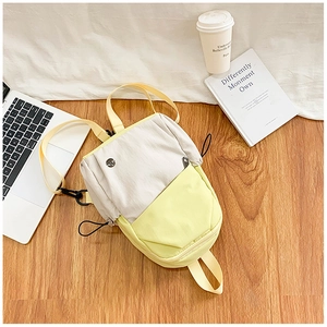 Vue détaillée d'un mini sac à dos bicolore avec détails de cordon sur bois