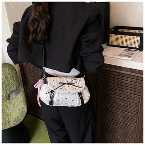 Detail of white pleated crossbody bag with black bow prints and pearl ribbon charm