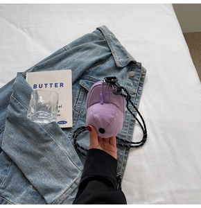 Detail view of purple cap-shaped crossbody bag with grid texture on denim jacket