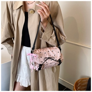 Detailed view of pink pleated handbag with black bow prints and pearl charm tassel