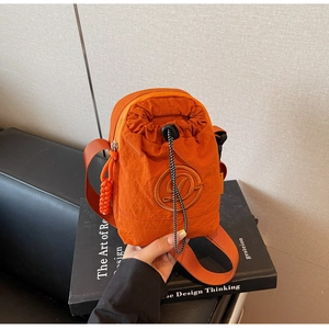 Close-up of orange nylon crossbody bag featuring a drawstring closure and embroidered logo