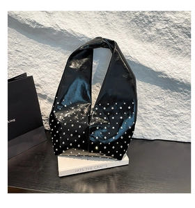 Detailed close-up of a black glossy punk-style tote featuring silver metal rivet decorations
