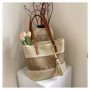 Detail der handgewebten Strohtasche mit Ledergriffen und dekorativer Holzperlen-Quaste