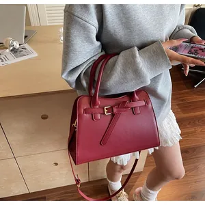Detail of burgundy leather handbag with decorative buckle and adjustable shoulder strap