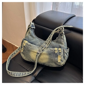 Detailed macro of vintage washed denim crossbody bag featuring distressed fabric on a sofa