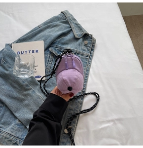 Macro shot of purple baseball cap shaped mini crossbody bag with dual zipper details