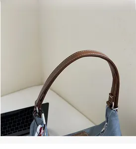 Detail eines blauen Denim-Shoppers mit braunem Kunstledergriff und weißen Kontrastnähten