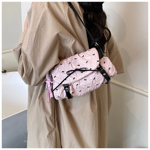 Detail view of pink ruffled shoulder bag with black bows and pearl charm accessory