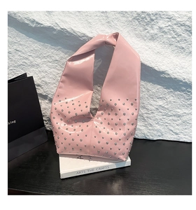 Detail of pink patent leather handbag with silver studs and unique knotted handle