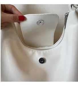 Détail macro du sac blanc montrant la finition lisse et le fermoir magnétique argenté