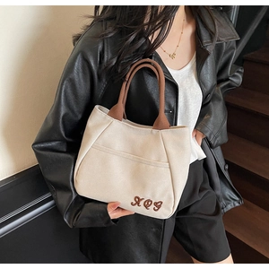Close-up of XOG letter embroidery and front pocket on off-white canvas tote bag
