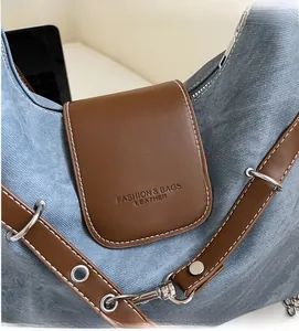 Detailansicht von blauem Denim-Stoff und brauner Lederklappe mit geprägtem Modeschriftzug