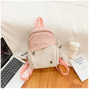 Detail of a pink and beige nylon mini backpack with a front zipper pocket and adjustable straps