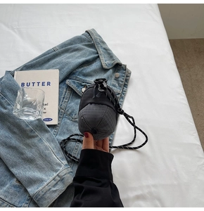 Detail of grey plaid baseball cap shaped mini bag on denim jacket with rope strap