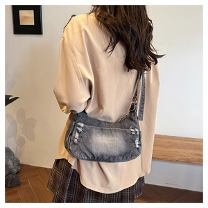 Detail view of washed grey denim shoulder bag with distressed texture and metal buckle