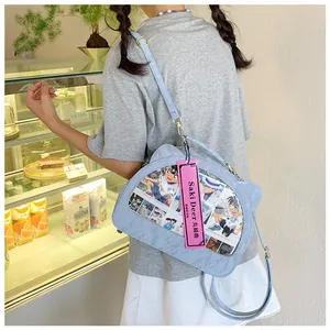 Detail of light blue cat-eared ita bag with transparent window showing anime cards