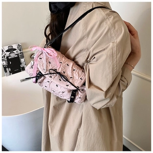 Close-up of pink quilted crossbody bag with black bows, pearls, and ribbon details