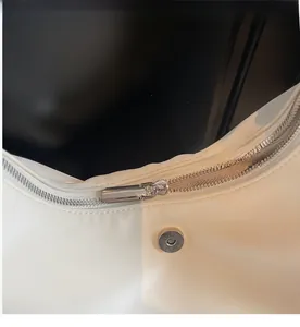 Détail de la fermeture éclair argentée et du bouton magnétique sur sac bandoulière blanc