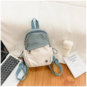Detail of multi-pocket canvas backpack with drawstring side pockets and laptop in background