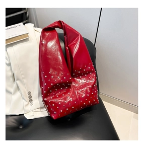 Detail of red glossy leather shoulder bag with silver rivet studs and soft structure