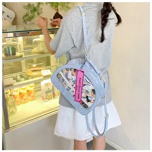 Detail of light blue ita bag with clear window showing anime cards and leather texture