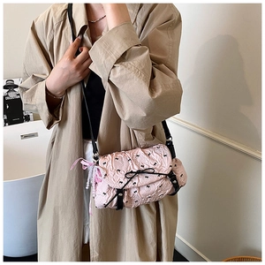 Detail of light pink pleated bag with black bow patterns and pearl chain strap