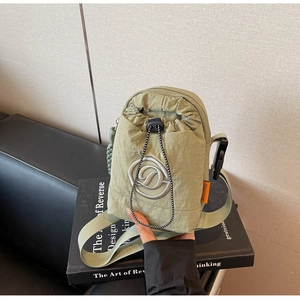 Detail view of light green nylon crossbody bag showing drawstring closure and orange label