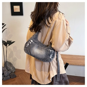 Detailed view of the distressed denim hobo bag featuring frayed edges and a washed finish