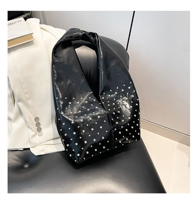 Detail of black glossy leather bag with silver studs on a white blazer background