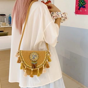 Detailed back view of a straw crossbody bucket bag featuring ethnic tassels and beadwork