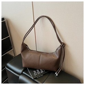 Close-up of dark brown hobo bag with unique knotted strap on a leather bench