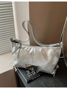 Silver metallic leather tote bag with vertical stitching and zipper detail in soft sunlight